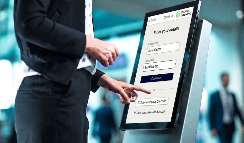 Visitor checking into an office using Matrix Booking digital display screen from ProDVX.